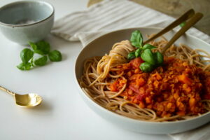 Teller mit veganer Linsenbolognese auf dem Esstisch